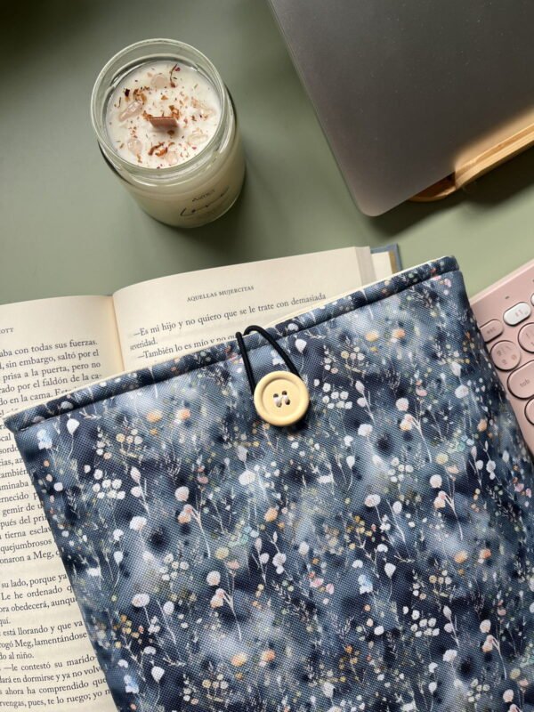 Funda literaria con exterior impermable. con Flores sobre fondo azul que asemeja una venta con agua tras la lluvia.